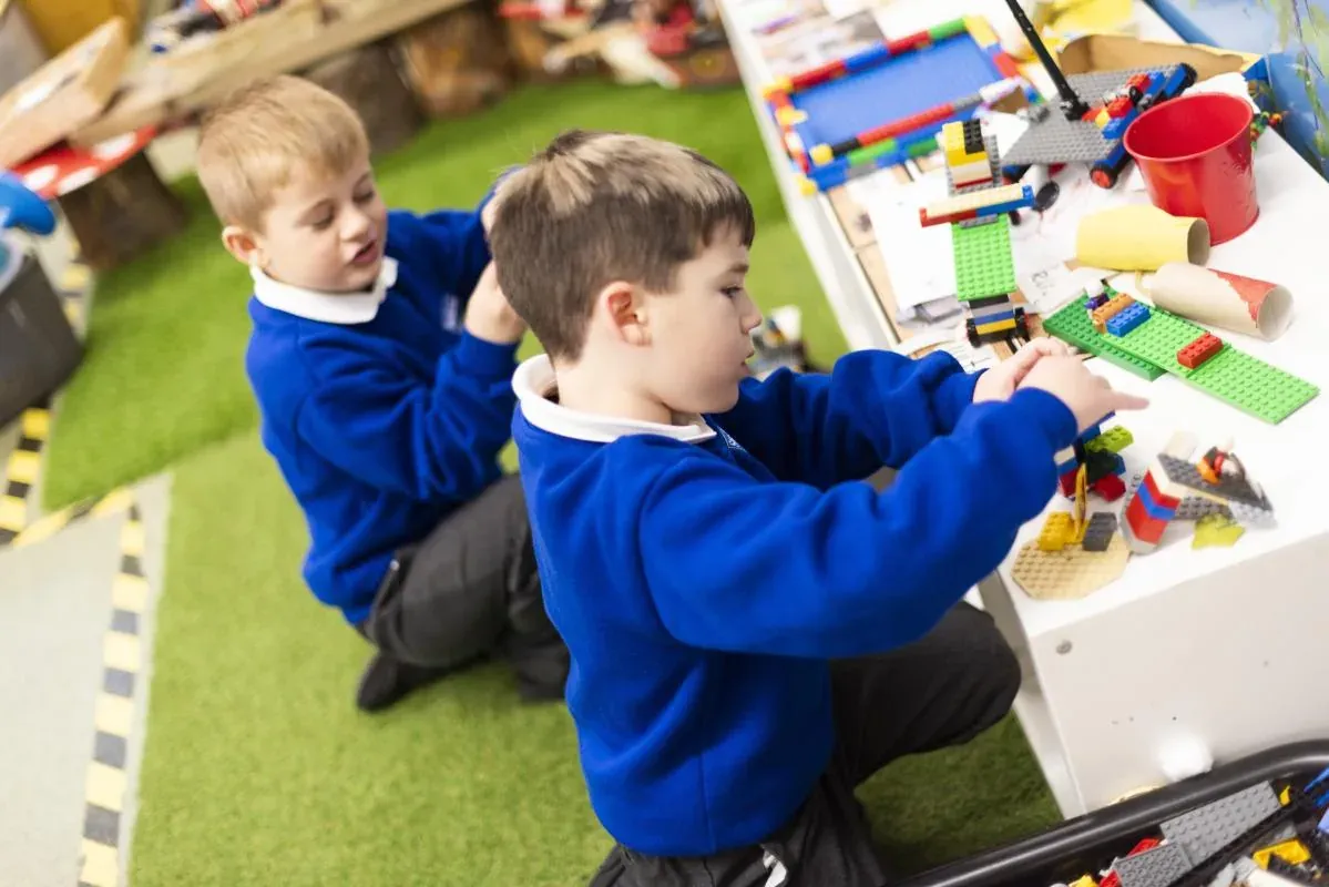 Two boys in blue school jumpers building with construction blocks