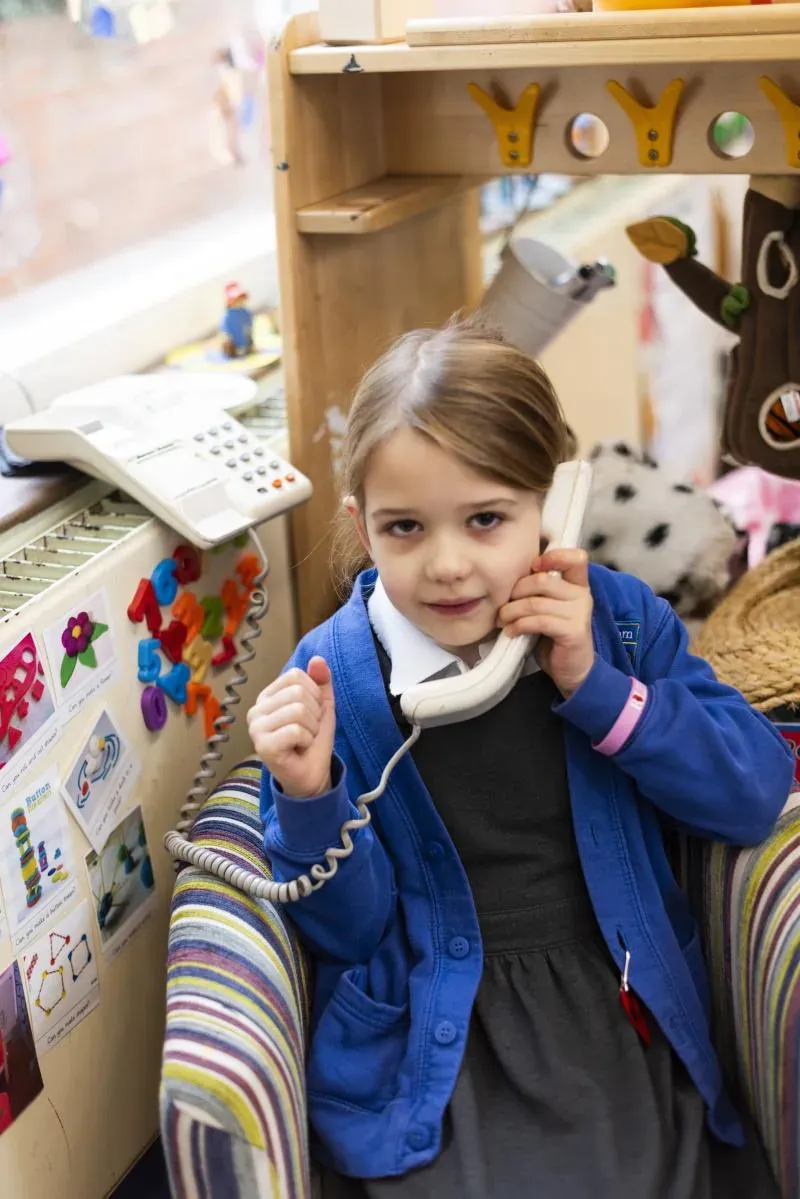 A young girl playing with a toy telephone in the role-play area
